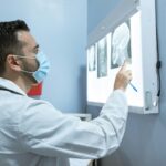 Allied Health Professional examining skull X-ray images on a lightboard during a medical diagnostic review.