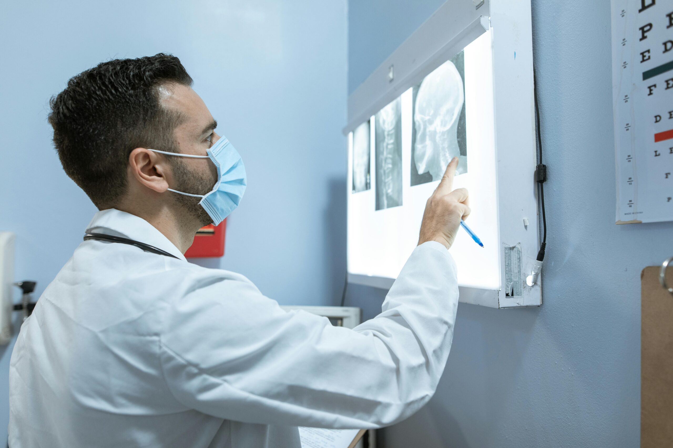 Allied Health Professional examining skull X-ray images on a lightboard during a medical diagnostic review.