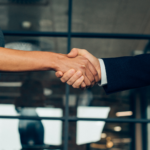 Healthcare facility administrator and staffing agency representative shaking hands over contract
